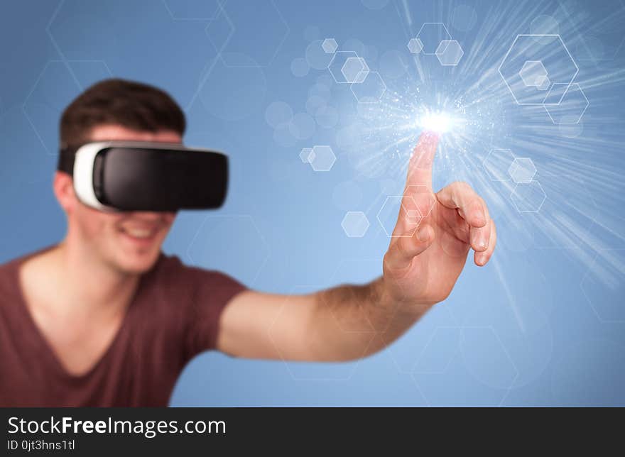 Young impressed man wearing virtual reality goggles with blue hexagons around him