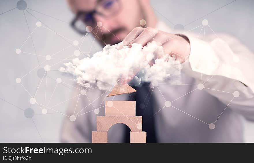 Young handsome businessman using wooden building blocks behind cloud concept. Young handsome businessman using wooden building blocks behind cloud concept