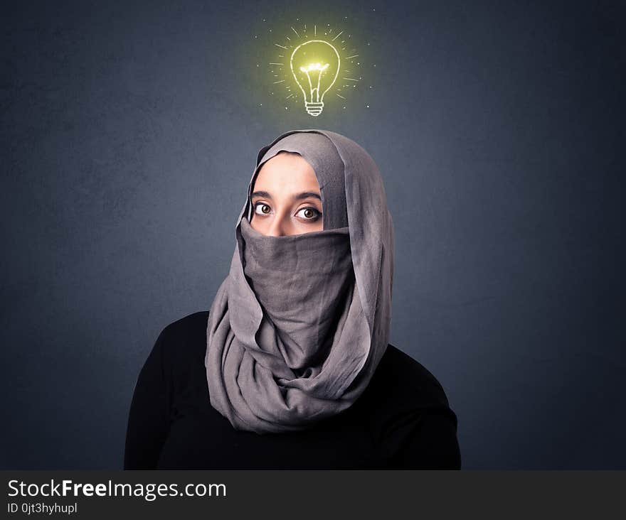 Young muslim woman wearing niqab with lit lightbulb above her head