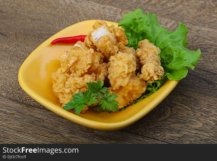 Crispy chicken nuggets with spices on wood background