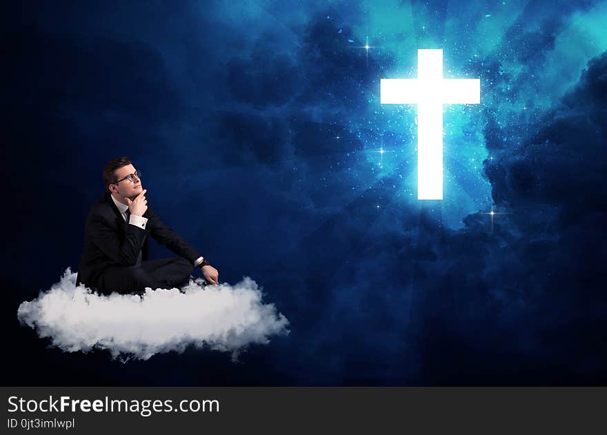 Man sitting on cloud lokking at a cross