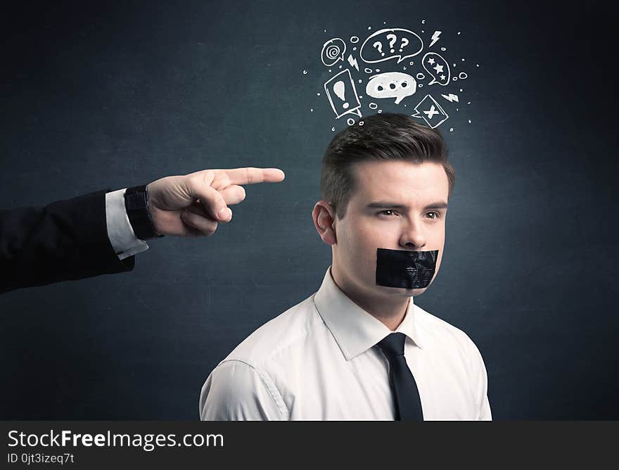 Caucasian business hand pointing at stressed male employee with drawn question, explamation marks, talk bubble above his head. Caucasian business hand pointing at stressed male employee with drawn question, explamation marks, talk bubble above his head