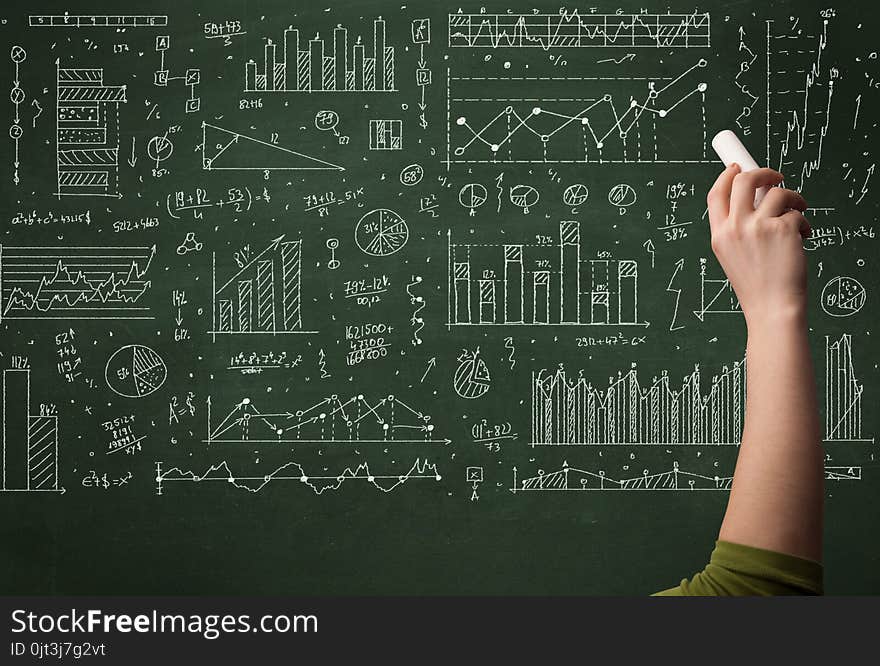 A hand drawing lines, pie charts, graphs on a green blackboard with a chalk. A hand drawing lines, pie charts, graphs on a green blackboard with a chalk