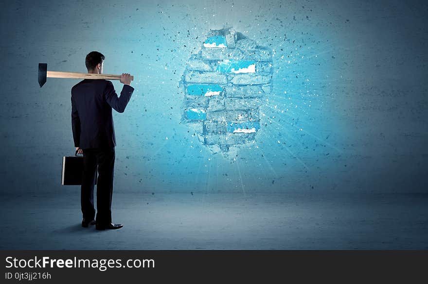 Business man hitting brick wall with huge hammer