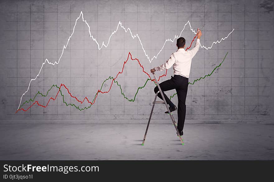 A guy in modern suit standing on a small ladder and drawing a chart on grey wall background with exponential progressing curves, lines. A guy in modern suit standing on a small ladder and drawing a chart on grey wall background with exponential progressing curves, lines