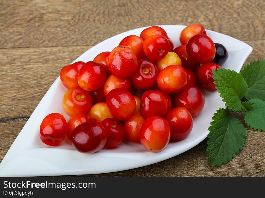 Sweet cherry in the bowl on wood background