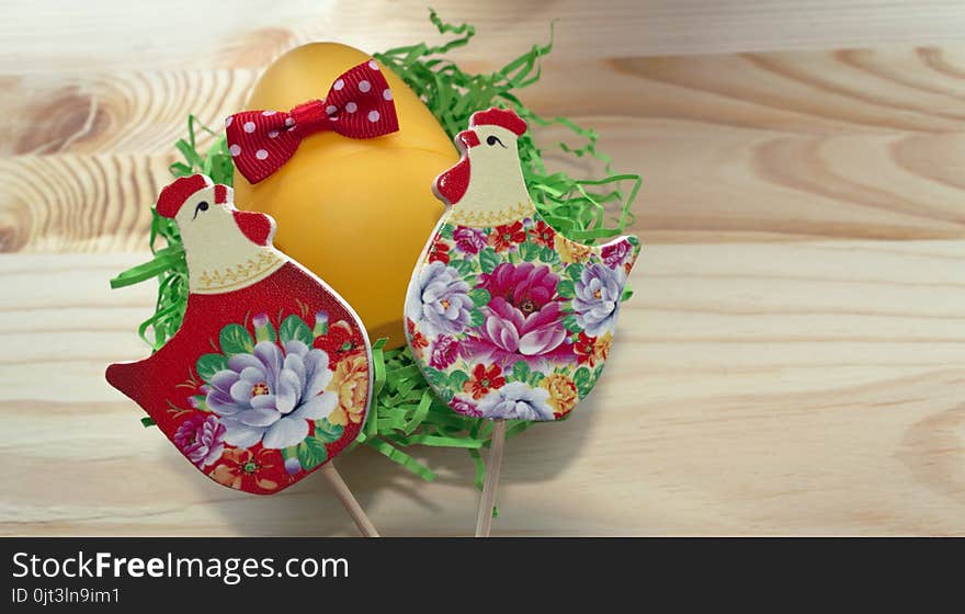 Close of view of hens and egg with red bow on wooden background