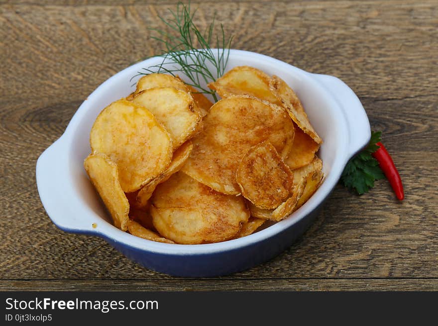 Natural potato chips heap in the bowl on wood background