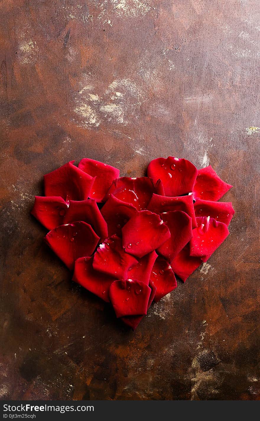 Top view flat lay red rose petals in heart shape on dark background. Romance, passion concept. Valentines day