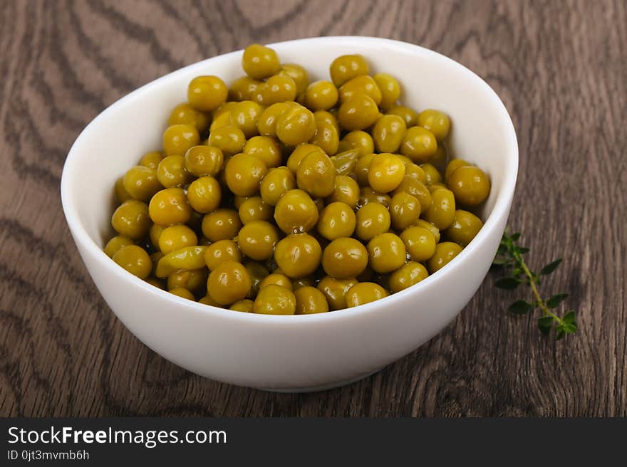 Pickled pea in the plate over wooden background