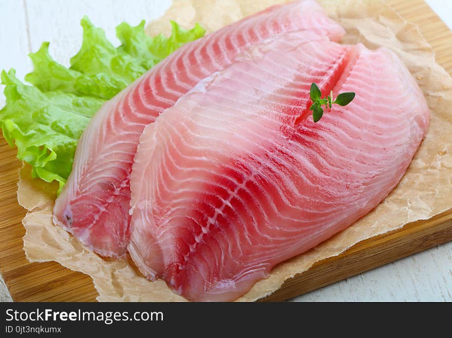 Raw tilapia fish fillet with thyme ready for cooking. Raw tilapia fish fillet with thyme ready for cooking