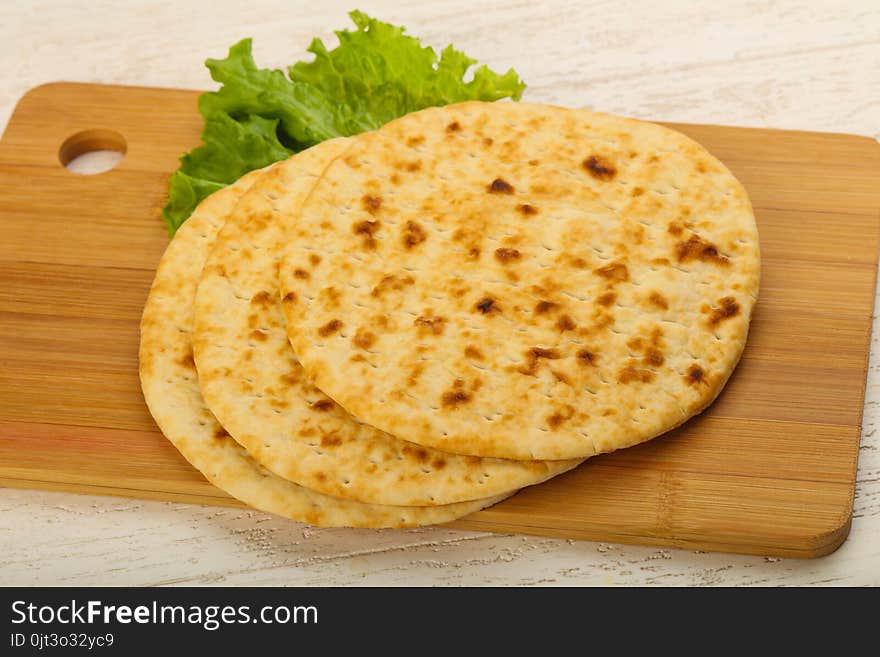 Pita bread with salad over wood background