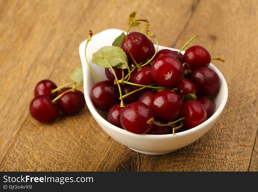 Cherry berries in the bowl on wood background