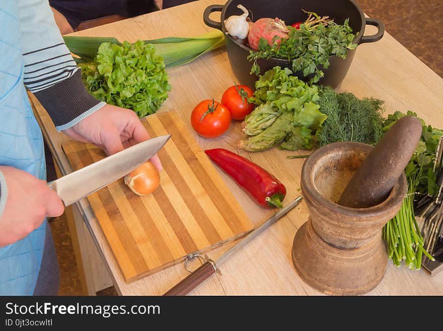 Male`s hands cooking healthy meal in the kitchen, behind fresh vegetables. Healthy Food. Cropped image of Man cutting vegetables