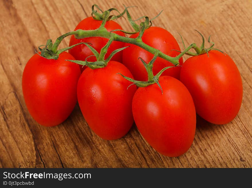 Fresh ripe juicy Tomato branch on the wood background