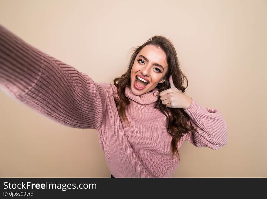 Beautiful Woman Smiling With White Teeth And Making Selfie, Photographing Herself Over Brown Background