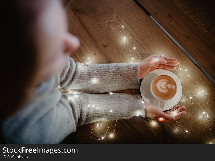 Girl holding coffee in hands over light bokeh background. Overhead shot. Girl holding coffee in hands over light bokeh background. Overhead shot.