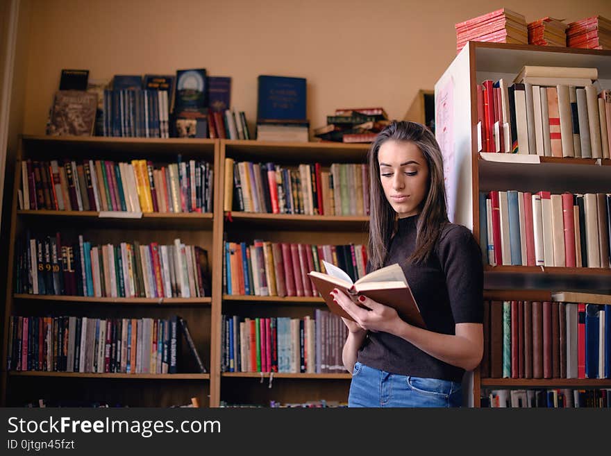 Woman studying in library, standing and reading book.