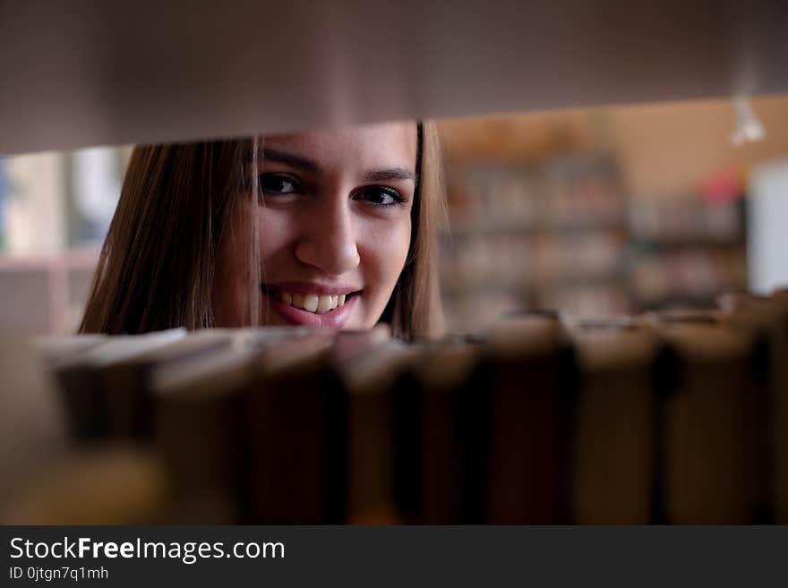 Young smiling woman looking through bookshelf. Young smiling woman looking through bookshelf.