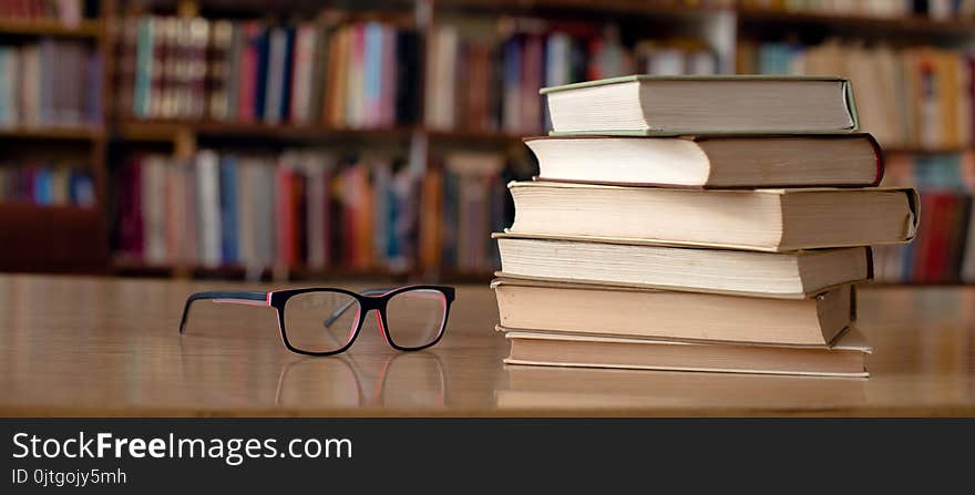 Books and eyeglasses on wooden desk in library. Books and eyeglasses on wooden desk in library.