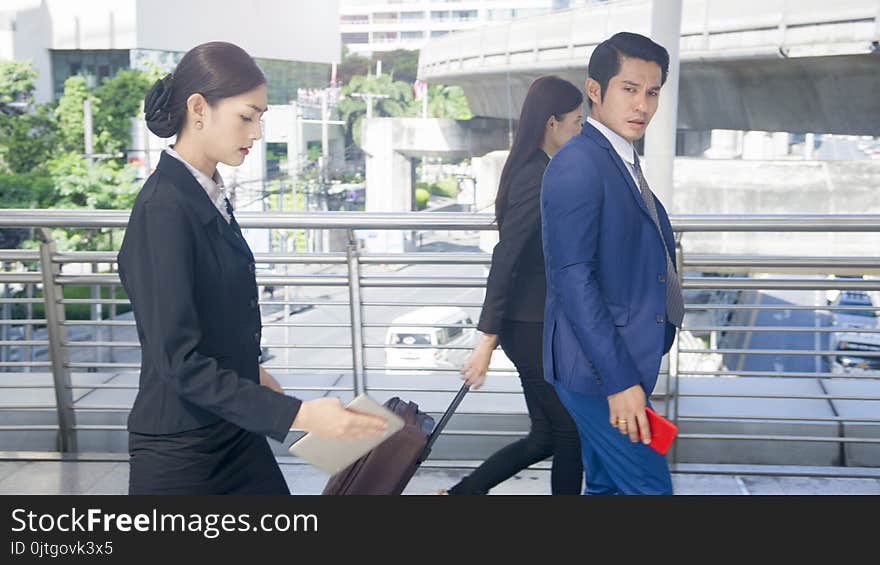 Group smart business people of men and women walk together in rush hour in feeling stress with tablet smart phone device and luggage at the outdoor pedestrian walkway space in the morning. Group smart business people of men and women walk together in rush hour in feeling stress with tablet smart phone device and luggage at the outdoor pedestrian walkway space in the morning.