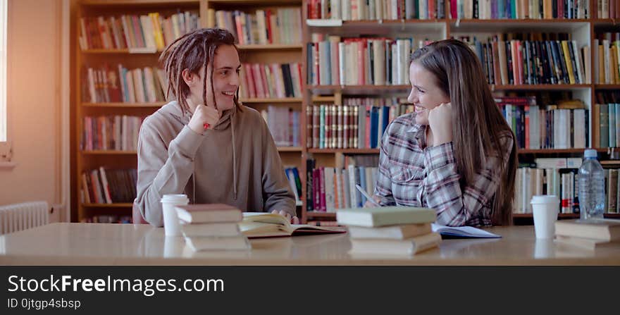 Lovely couple learning together in library, smiling and looking at each other,