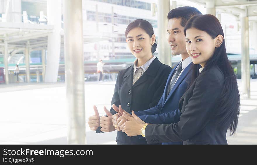 Group of business people of men and women stand and thumb up together in the feeling of happy and success at the outdoor pedestrian walk way. Group of business people of men and women stand and thumb up together in the feeling of happy and success at the outdoor pedestrian walk way