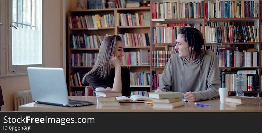 Female and male student in library, learning and laughing. Female and male student in library, learning and laughing.