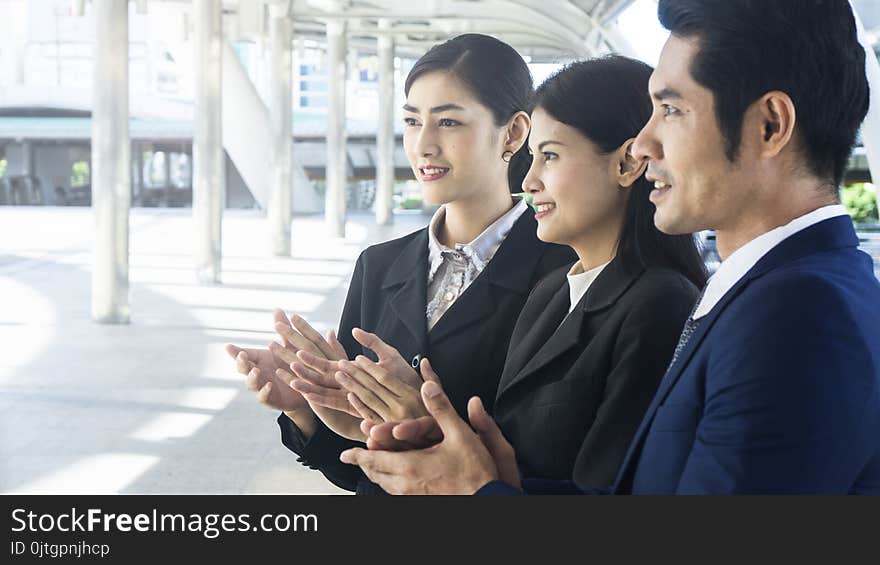 Group of smart people of men and women stand and clap hands in the feeling of happy and success at the outdoor pedestrian walk way. Group of smart people of men and women stand and clap hands in the feeling of happy and success at the outdoor pedestrian walk way