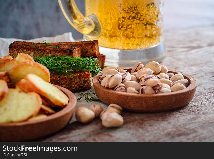 A glass of light beer, pistachios and rusks on a wooden table. A glass of light beer, pistachios and rusks on a wooden table