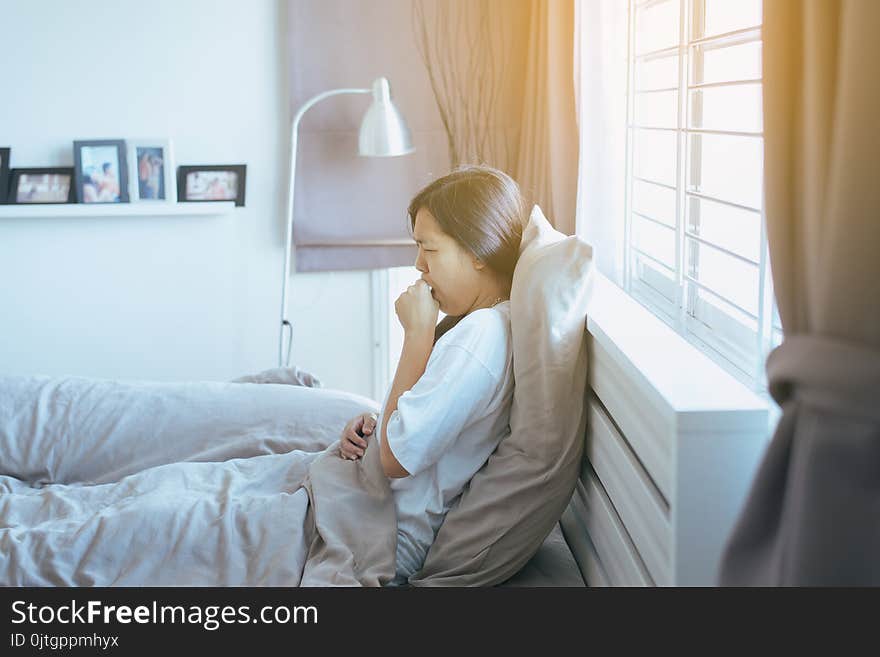 Young asian woman coughing and sitting on her bedroom,Concept of health