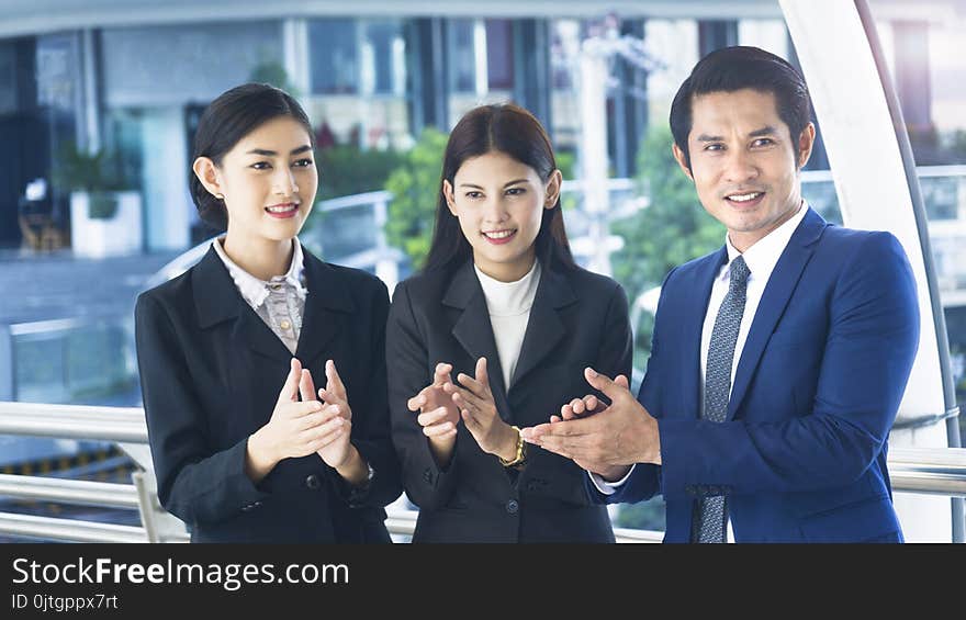 Group of smart people of men and women stand and clap hands in the feeling of happy and success at the outdoor pedestrian walk way. Group of smart people of men and women stand and clap hands in the feeling of happy and success at the outdoor pedestrian walk way