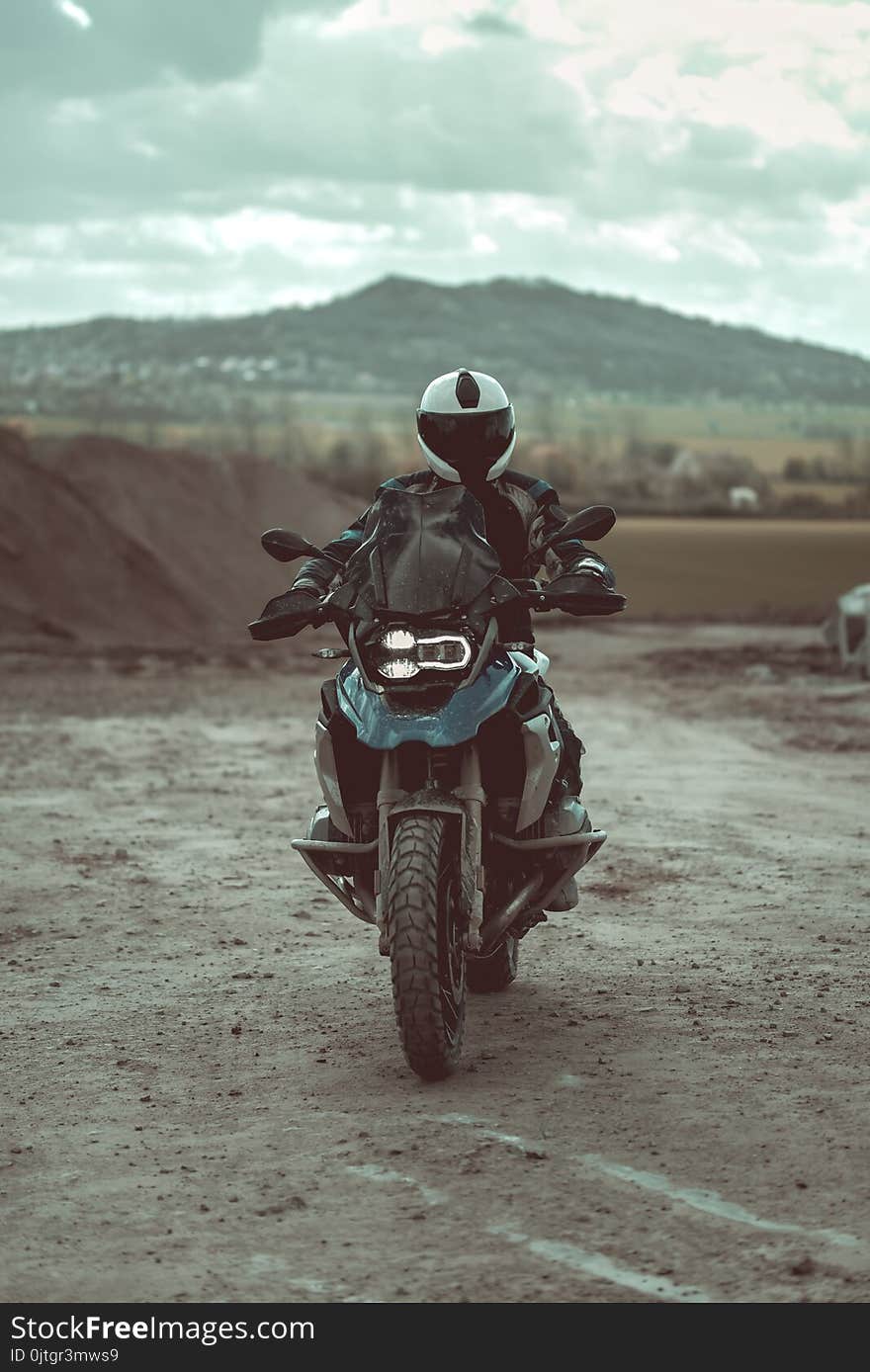 Motorcyclist with helmet and motorbike outfit riding on the modern motorbike. Beautiful mountains visible in the background.