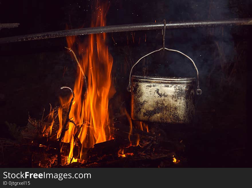 Boiling water in the bowler on the bonfire. Hiking romance around the campfire at night.