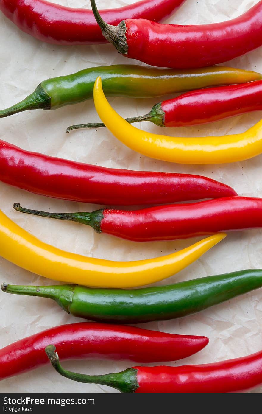 Vibrant hot peppers: red, yellow, green, raw on crumpled paper, top view. Vibrant hot peppers: red, yellow, green, raw on crumpled paper, top view.