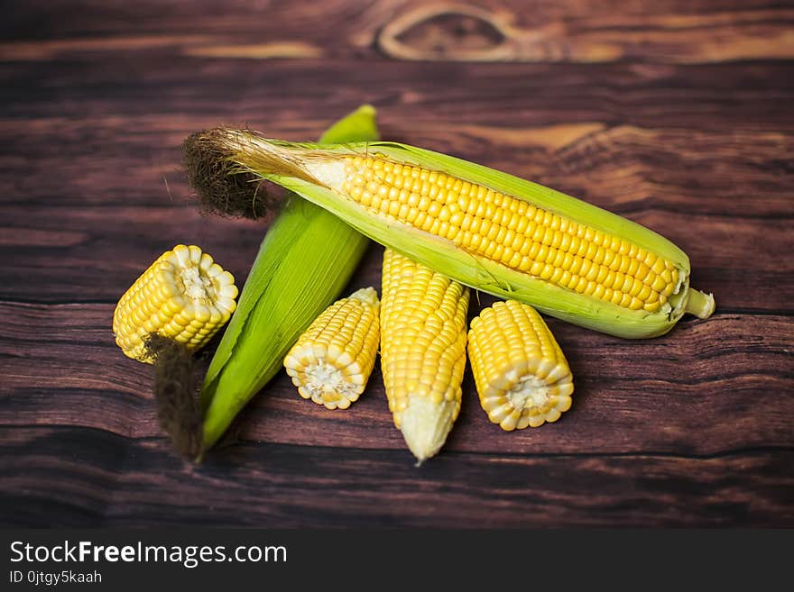 Fresh corn on cobs on wooden table, closeup, top view.