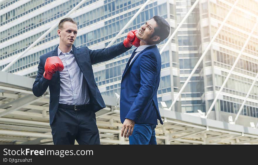 Two business mans are fighting with boxing glove at outdoor city