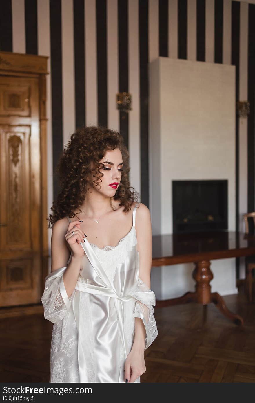 Young Beautiful Girl In A White Robe Is Standing In The Room