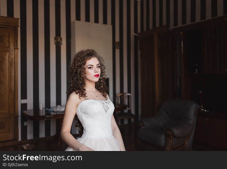 Beautiful bride is standing in a room by the window