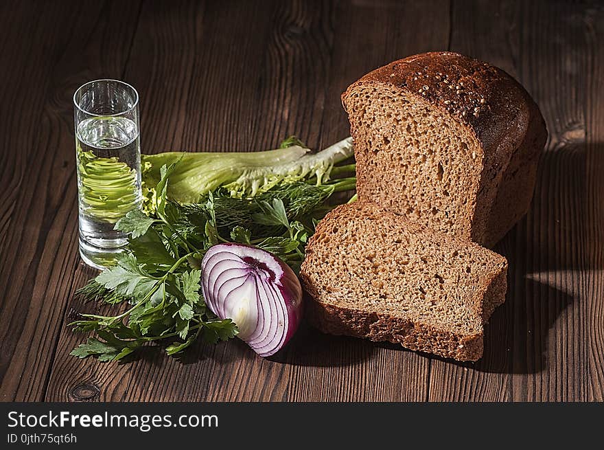 Stack of vodka and a simple snack - greens, half a bulb and a black bread on a dark rustic table. Stack of vodka and a simple snack - greens, half a bulb and a black bread on a dark rustic table