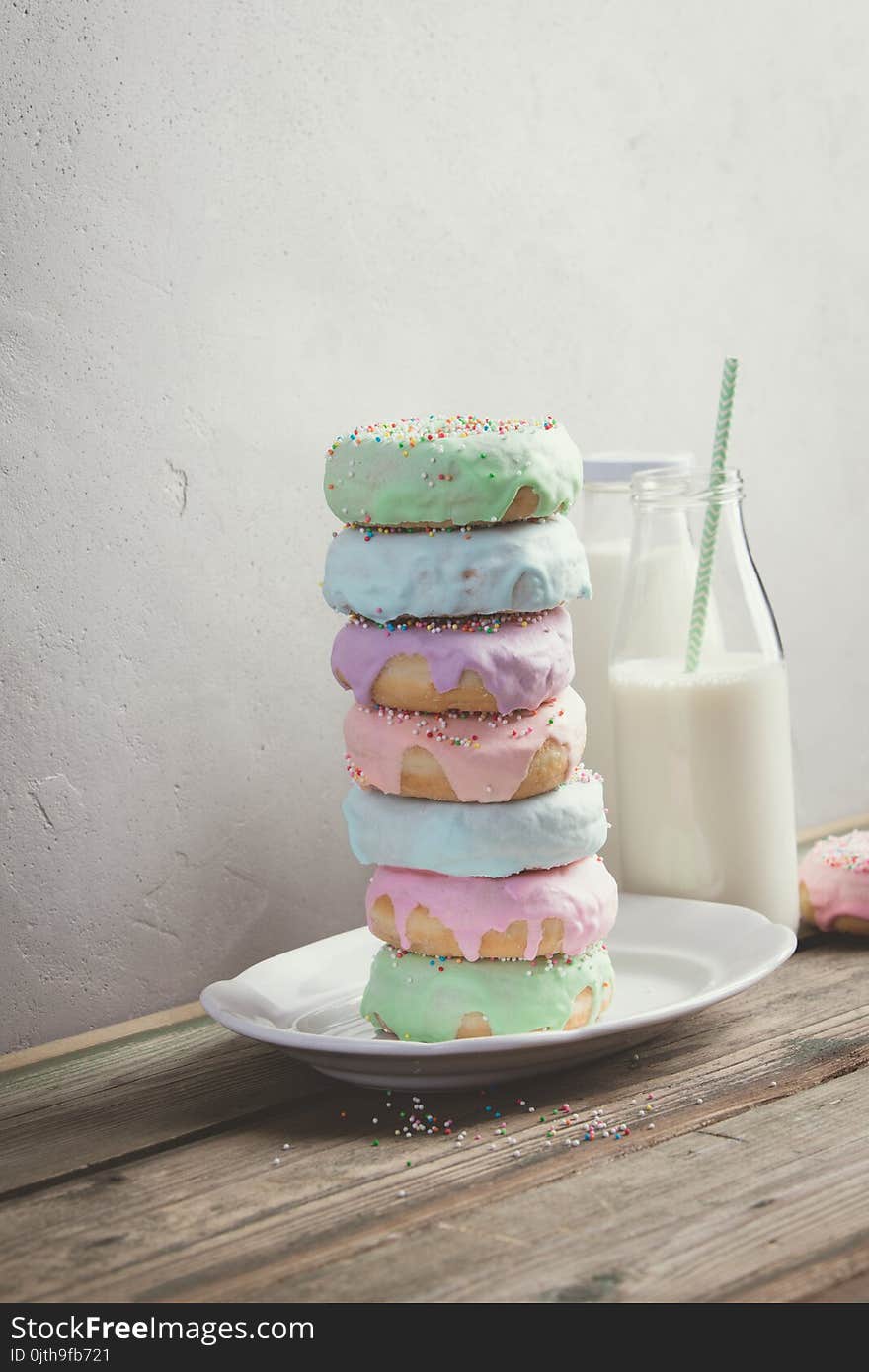 Doughnuts and a glass jar of milk with a straw on a wooden table. Doughnuts and a glass jar of milk with a straw on a wooden table