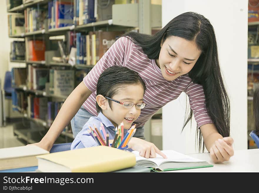 Woman teacher and kid student learn with book at bookshelf background