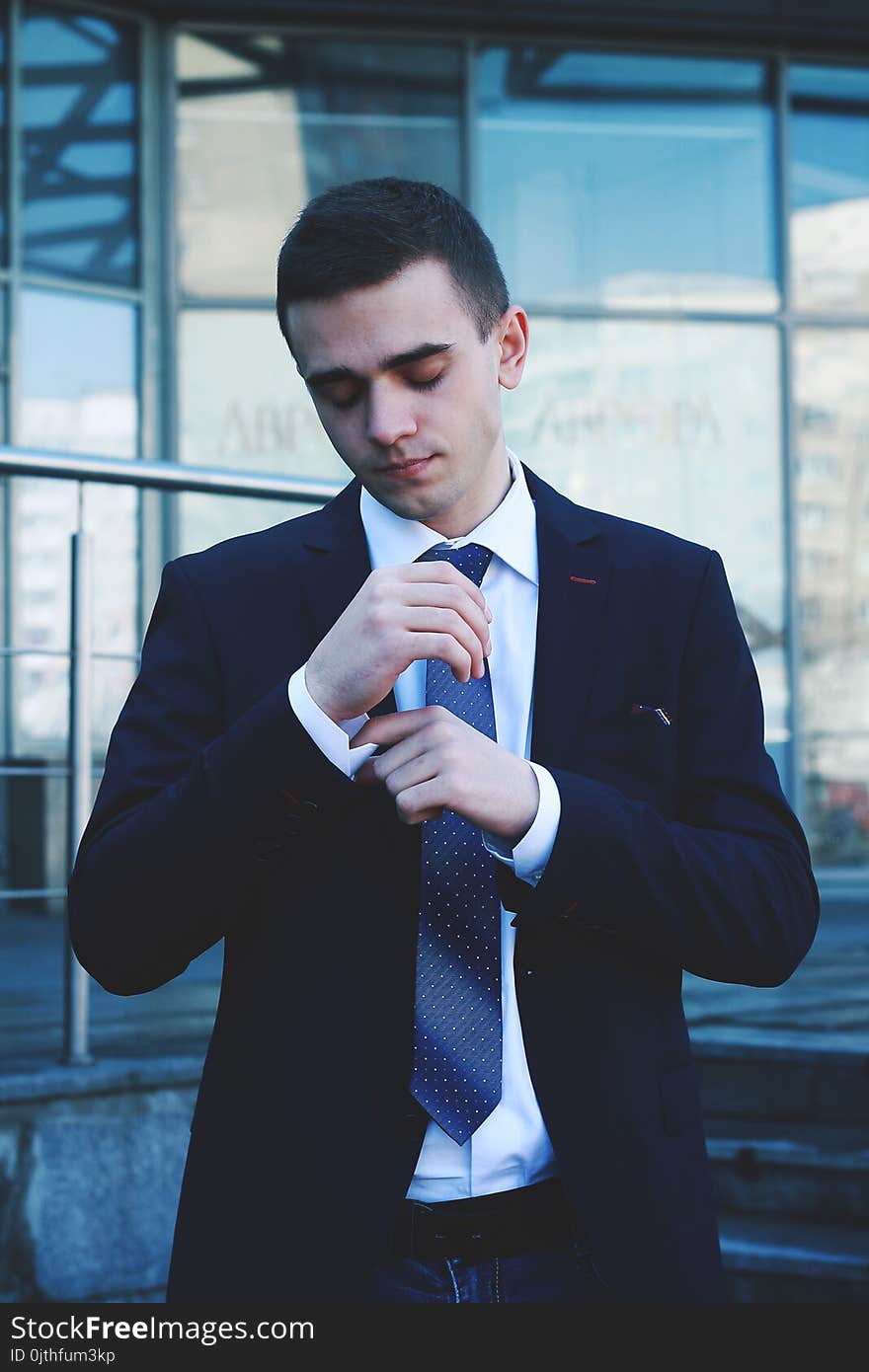 Elegant young fashion man looking at his cufflinks while fixing them.