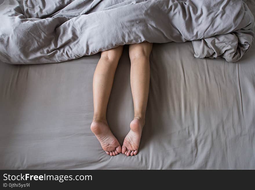 Close up of barefoot and leg under blanket on the bed