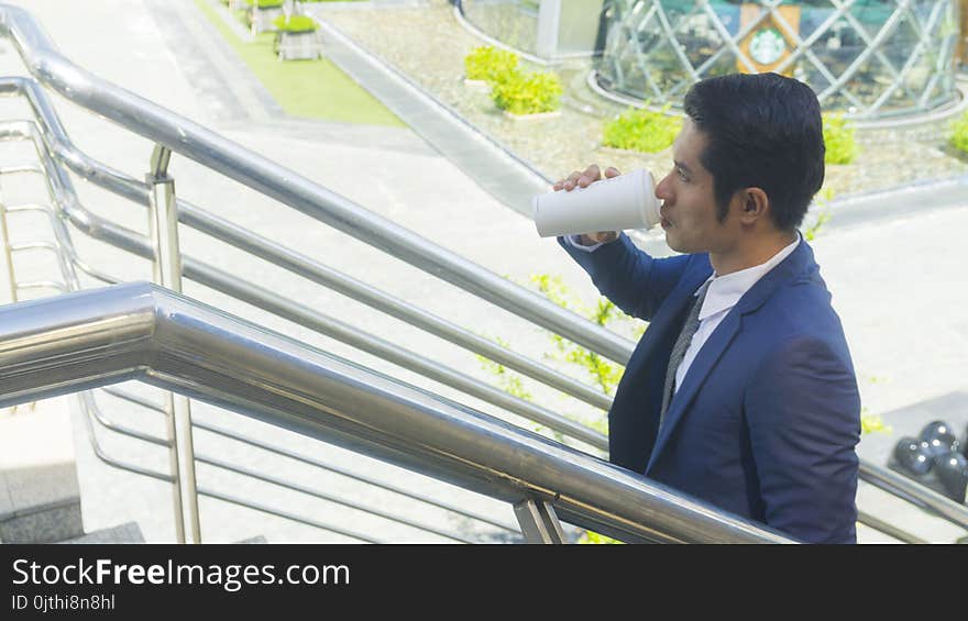 a business asia man drink coffee with paper cup of drink at outdoor