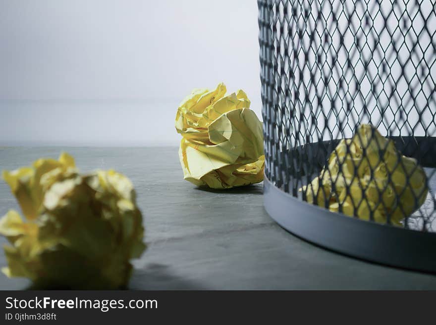 Focus Photo of Yellow Paper Near Trash Can