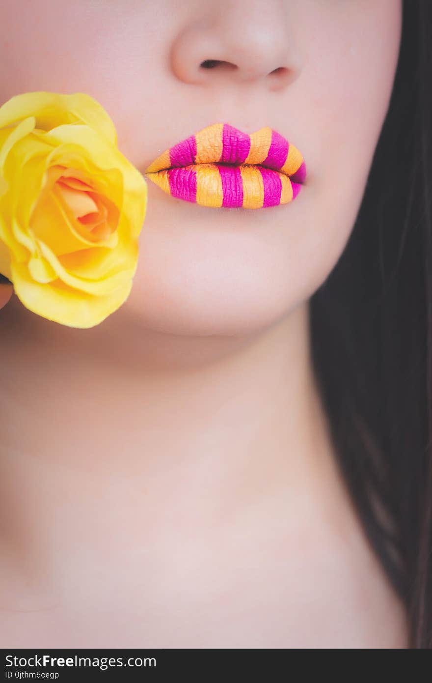 Woman Wearing Yellow and Pink Striped Lipstick Holding Yellow Rose