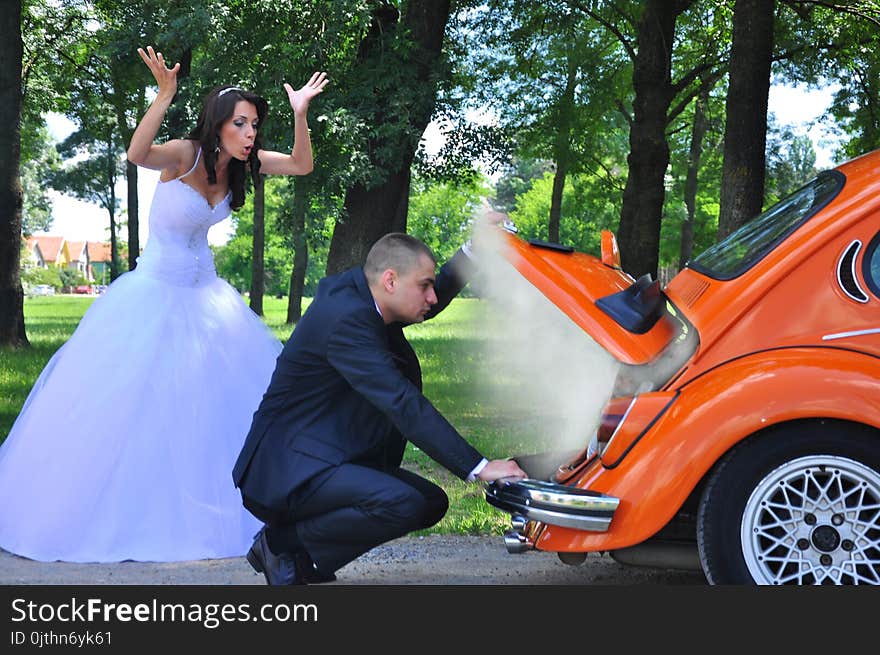 Woman in White Wedding Gown Near Orange Car