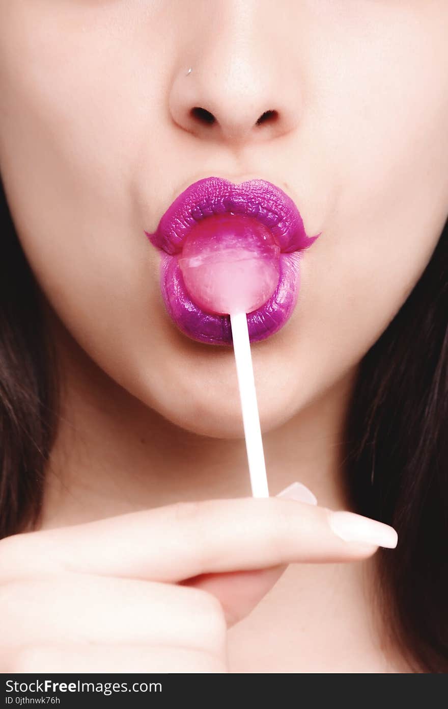 Woman Wearing Purple Lipstick With Pink Lollipop