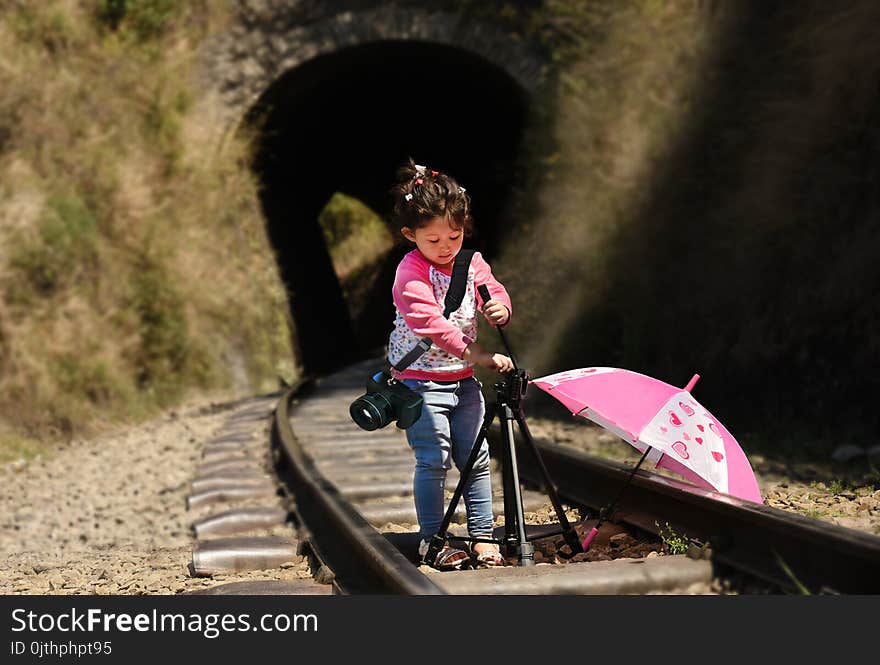 Little girl photographer with tripod and DSLR camera strapped on her neck